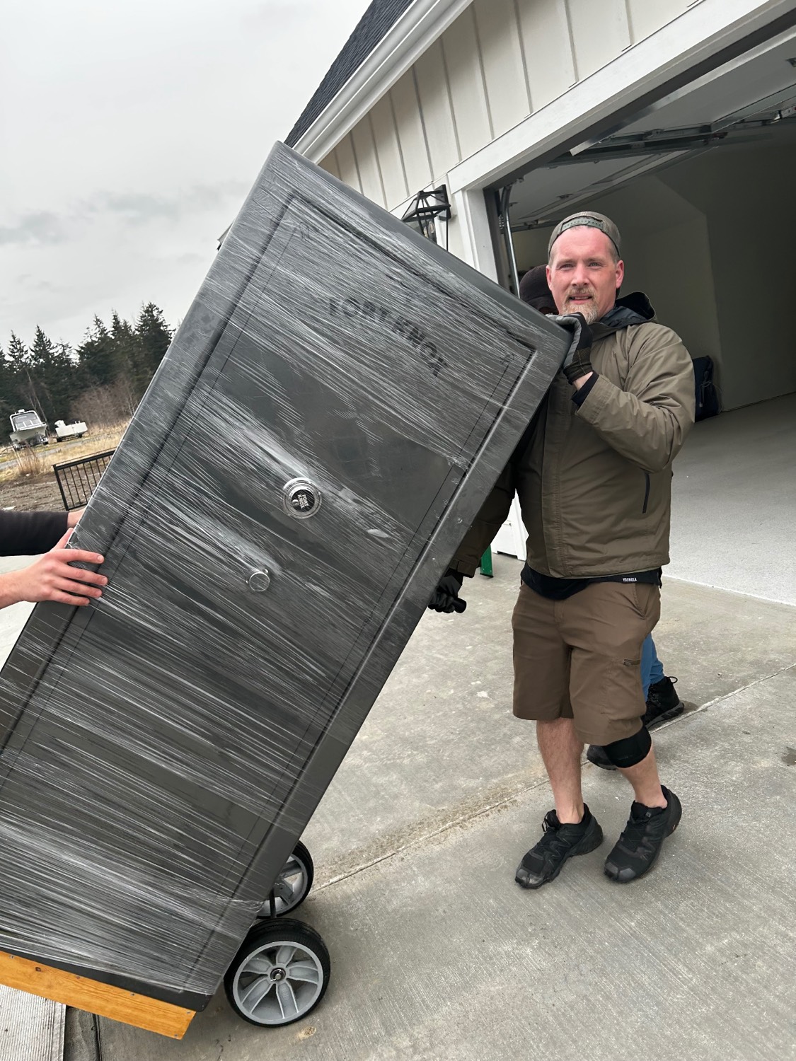 Lake Union Movers mover wheeling a shrink-wrapped gun safe on a dolly