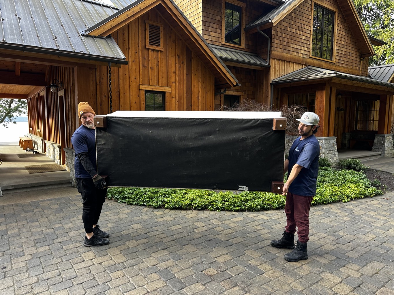 Lake Union Movers crew carrying a blanket-wrapped piece across a Seattle driveway